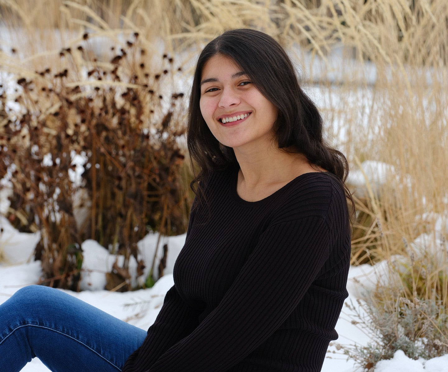 Alexis Garcia in a snow-covered field of dried flora 