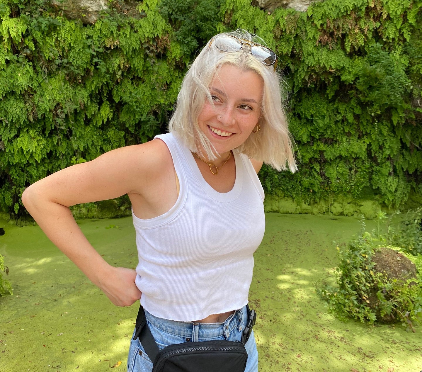 Honour posing on grass in front of vegetation growing on a stone wall