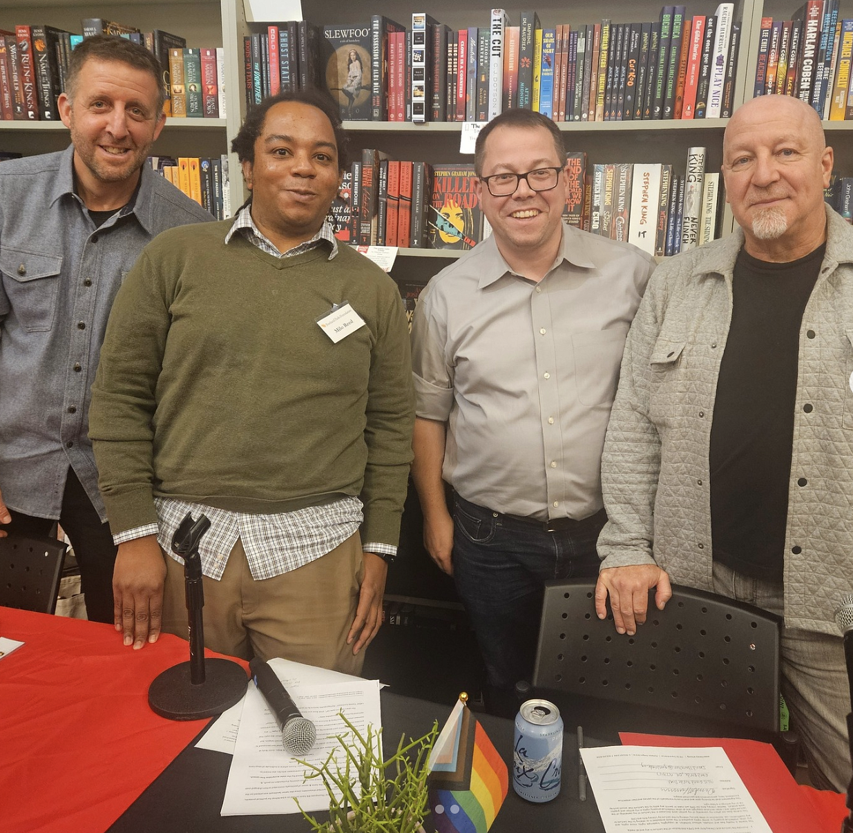 Keith, far right, joined by the other speakers and moderator at Literary Arts. Shows four individuals in front of a large book shelf filled with books.