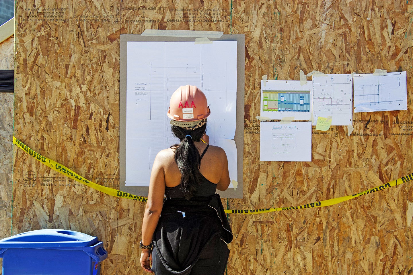 BDI photo of a student in front of a building diagram on a construction site. 