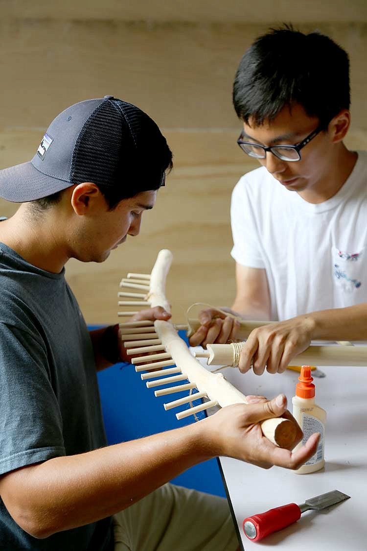 Two men working on a wooden tool