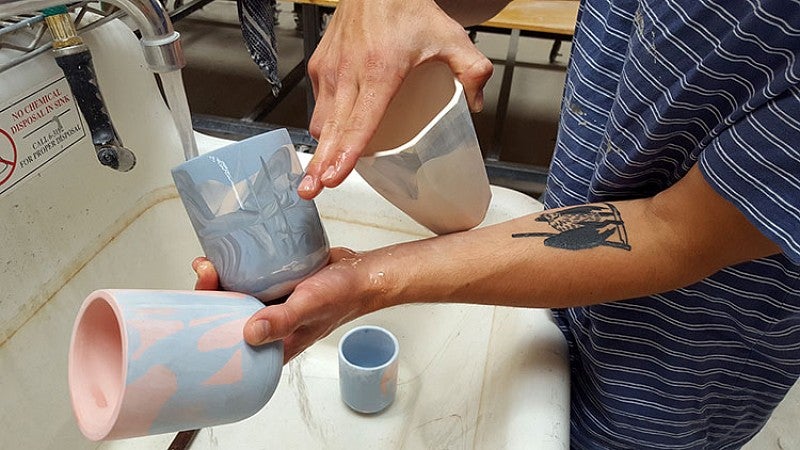 Thomas Sprott washes ceramic cups in sink. Photo by Marti Gerdes.