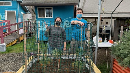 Students pose behind a raised plant bed at Opportunity Village