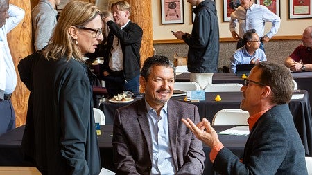 Photograph of three deans talking at the SCYP luncheon. 