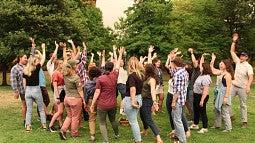 RARE cohort come together outside for a team building exercise that includes a beach ball. Three individuals are pictured. 