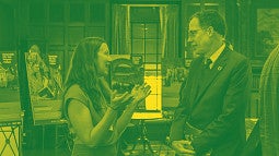 SCYP kick-off photograph showing communication lead, Lindsey Hayward and UO President Karl Scholz talking. Photograph is colored as a duotone in UO green and yellow. 