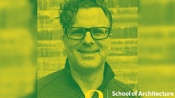 Uli Dangel's headshot. Shows a smiling man with glasses in front of a light brick wall. Photo is a yellow and green duotone.