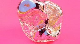 a mirror rock sculpture on pink background