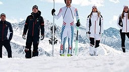 people stand in snow wearing Winter Olympics gear