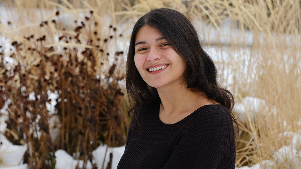 Alexis Garcia in a snow-covered field of dried flora 