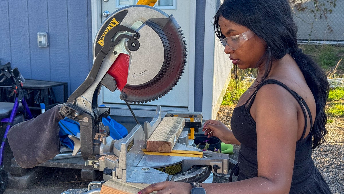 Student cuts wood for the outdoor kitchen. 