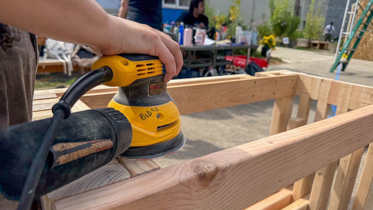 Student works on sanding a part of the wooden structure. 