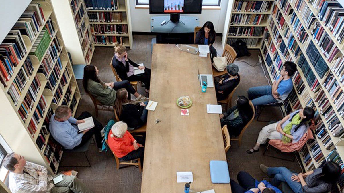 People sitting around a long table with books