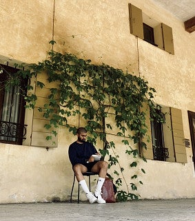 Yash notetaking in front of a yellowed concrete building