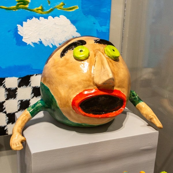 ceramic sculpture of a cartoonish head with arms 