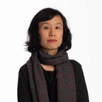 Photograph of Joyce Cheng. Shows a femme presenting individual looking into the camera in front of a white background. 