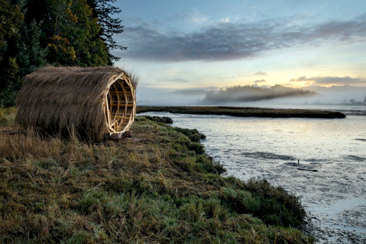 wooden cylinder structure in a field on a body of water