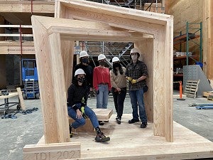 A team of student's posing in a wooden structure they created.