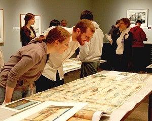 students examine artwork on table