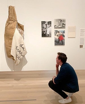 Liam Maher crouches at an art exhibition