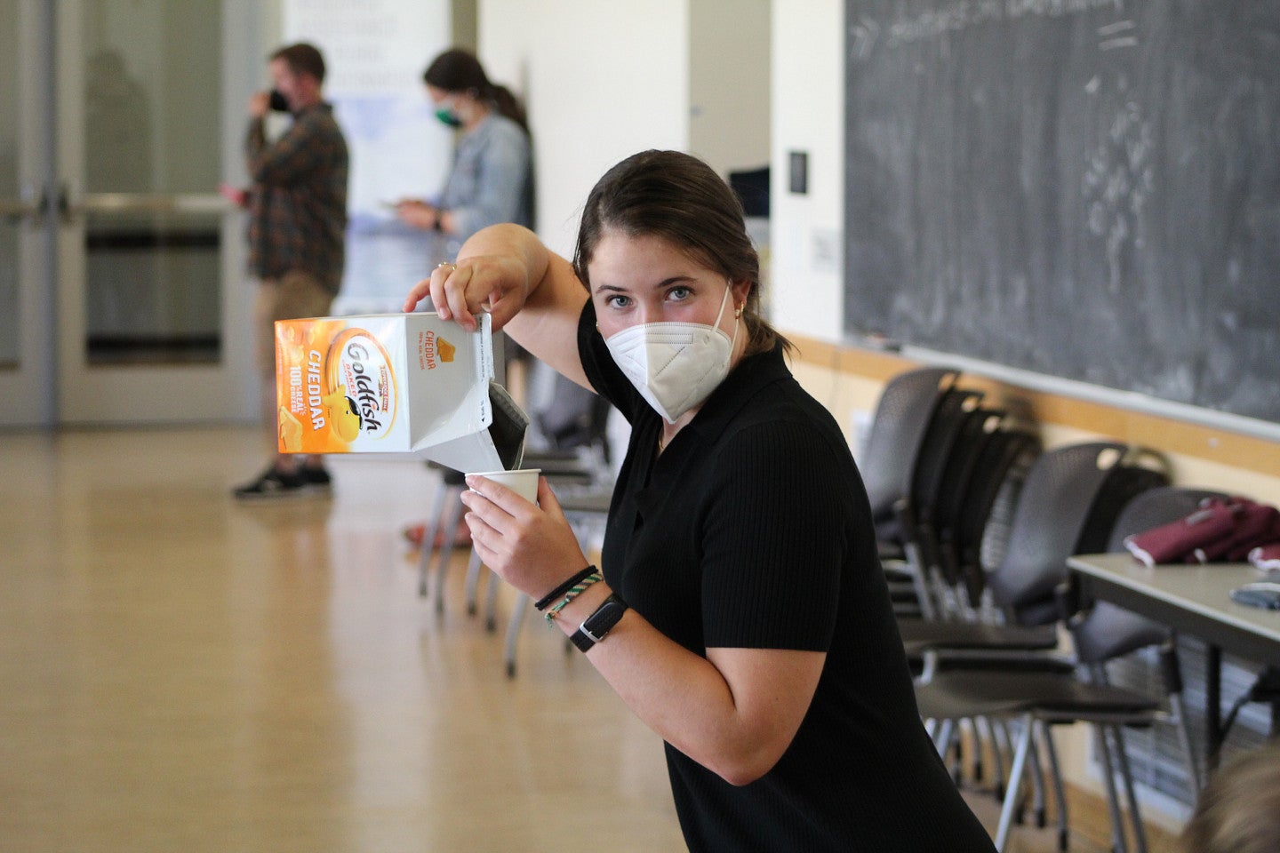 Photo of a masked RARE cohort member pouring the snack, Goldfish, into a cup. 