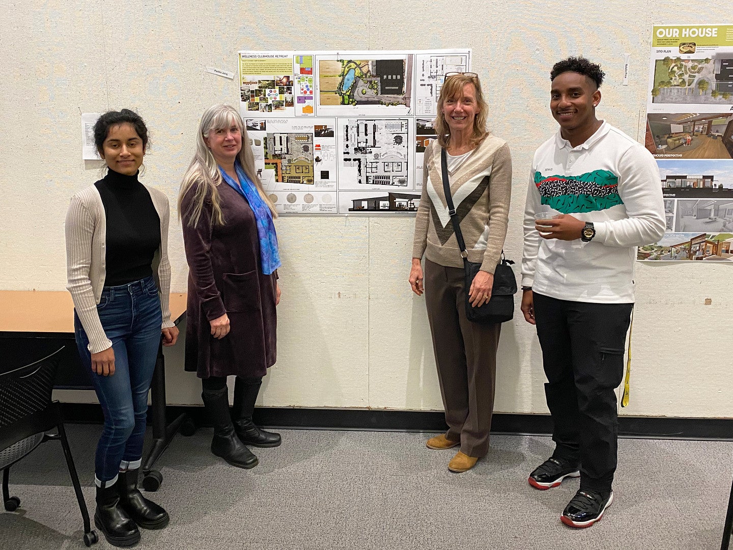 2 interior architecture students and 2 Arc workers posing with a student project depicting the Arc clubhouse