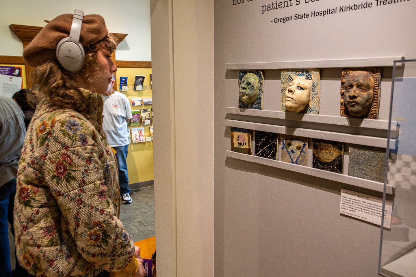 student looking at ceramic faces created by former patients
