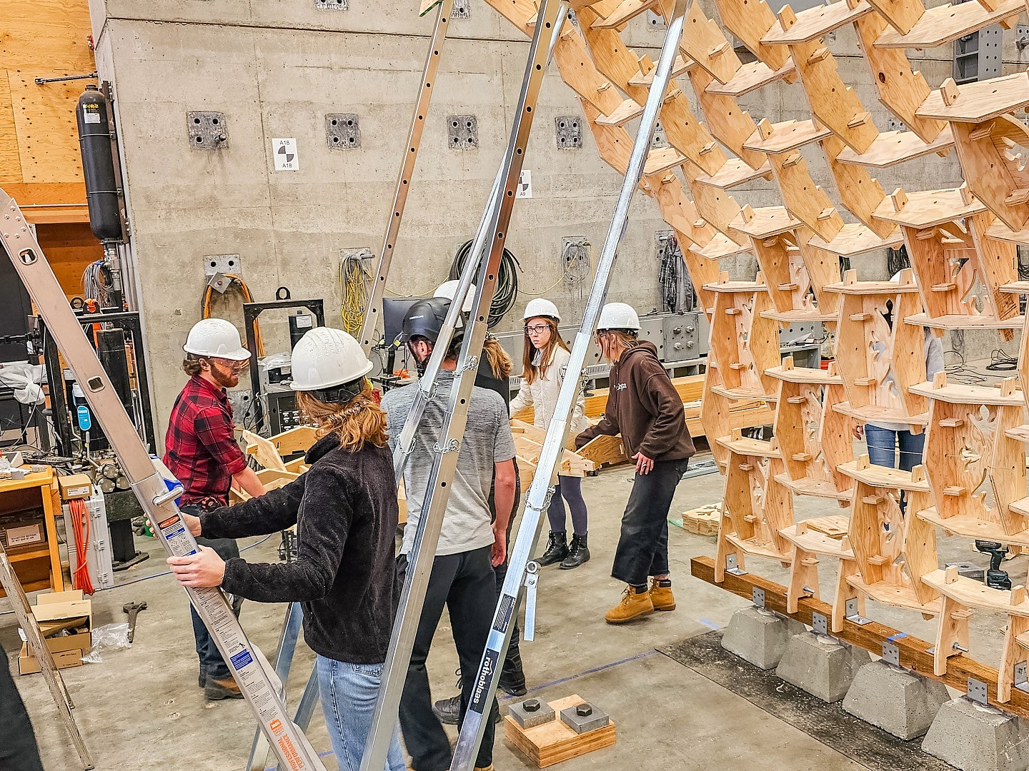 students bracing the arch structure with metal extension poles.