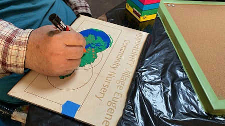 An Opportunity Village community member works on a nursery sign.