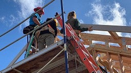 Photo of students constructing house against a blue sky