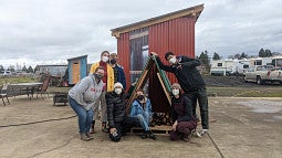 Everyone Village firewood shed with students posed in front