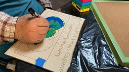 An Opportunity Village community member works on a nursery sign.