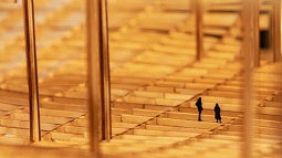 Photo of an architecture exhibit at the 2023 ECC Architecture Biennale. Close-up of a wooden structure with small shadow cut-outs of people in the model.