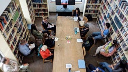 People sitting around a long table with books