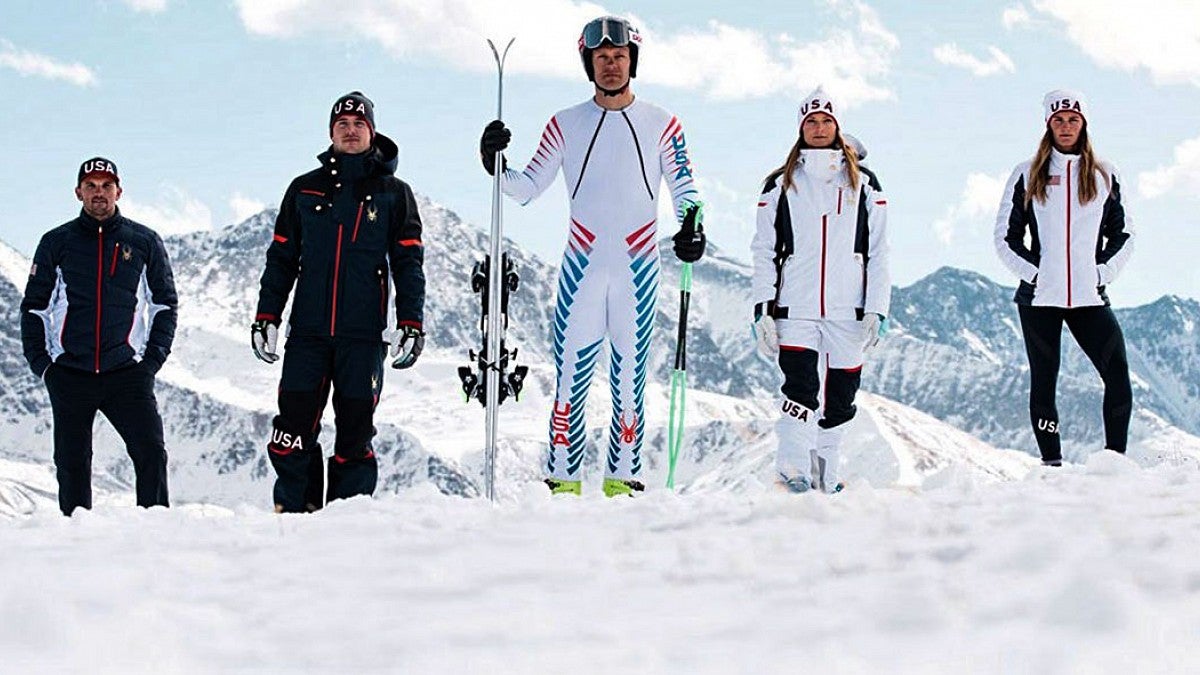people stand in snow wearing Winter Olympics gear