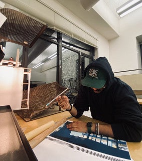Yash working on a cardboard model for an architecture studio class